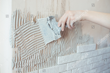 stock-photo-close-up-of-ceramic-tiles-with-glue-on-the-wall-worker-applies-tile-adhesive-to-the-wall-make-1946564140